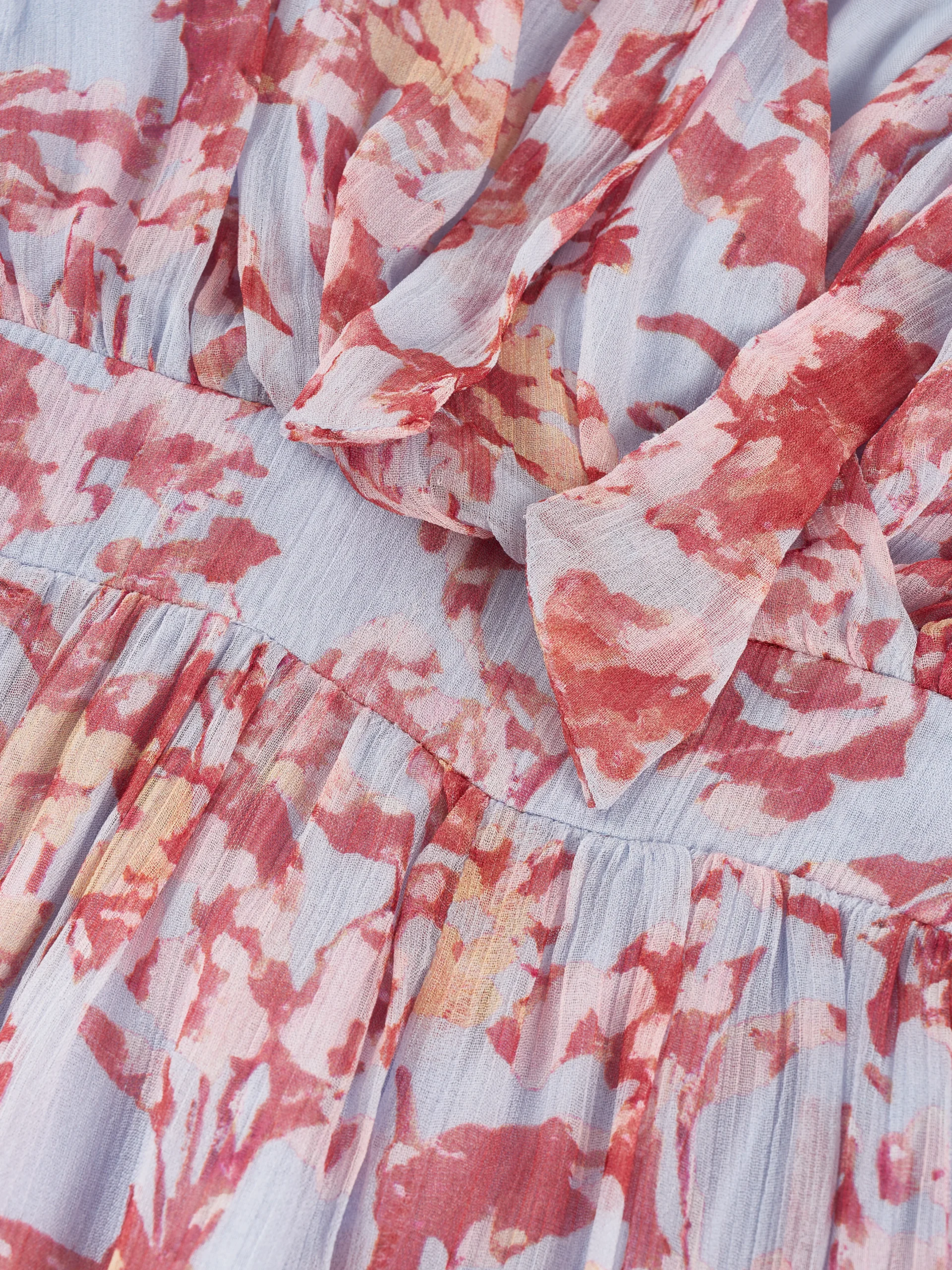 A lightweight floral mini dress featuring a feminine tie neckline, flutter sleeves, and a softly gathered waist. Its airy silhouette makes it ideal for summer collections, resort wear, and effortless everyday styling.
