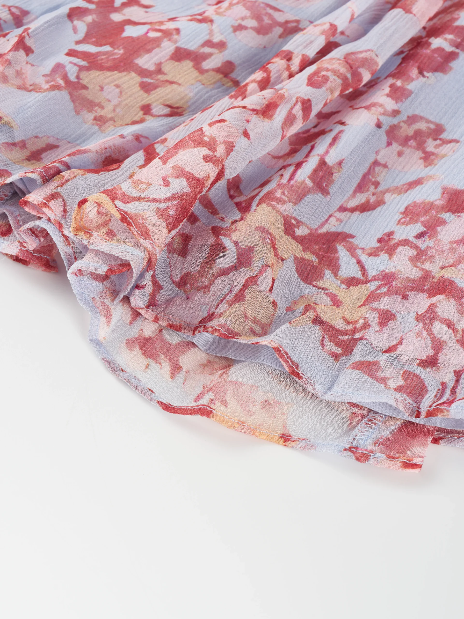A lightweight floral mini dress featuring a feminine tie neckline, flutter sleeves, and a softly gathered waist. Its airy silhouette makes it ideal for summer collections, resort wear, and effortless everyday styling.