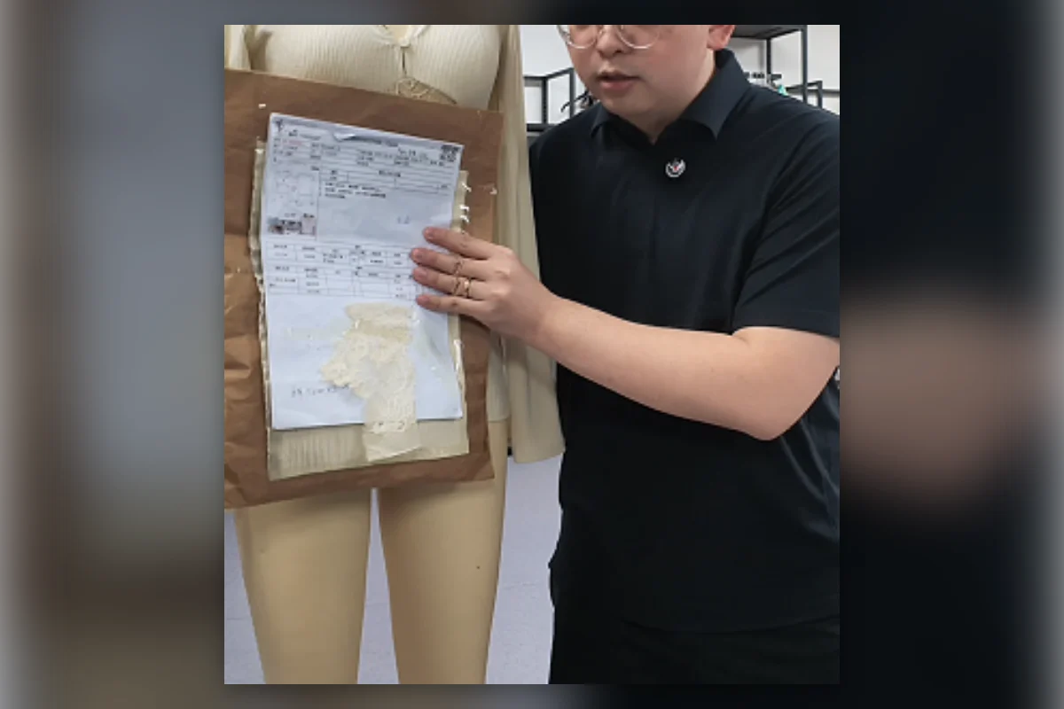 Shengfu product developer reviewing a Tech Pack and fabric swatches beside a sample garment