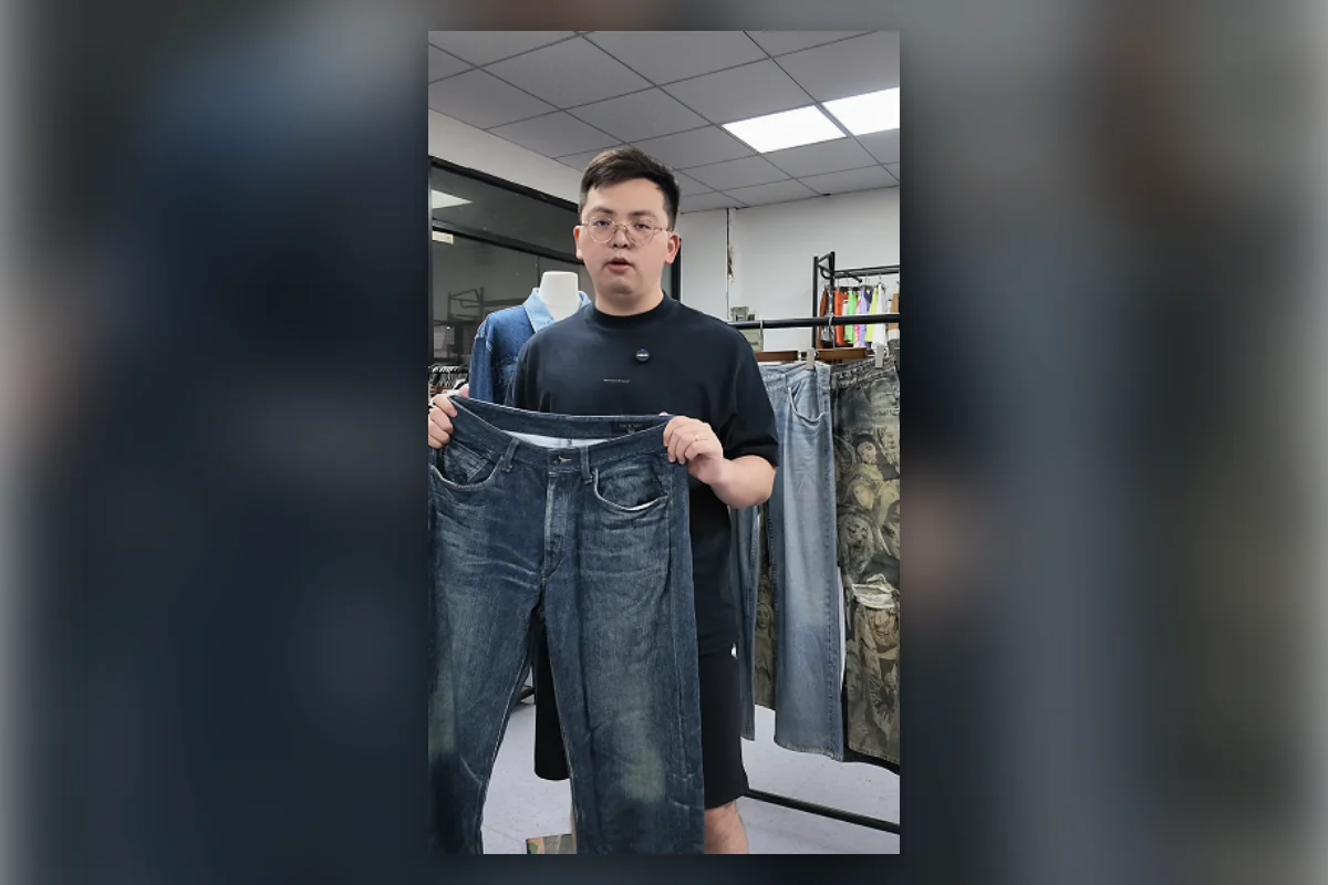 Shengfu product developer holding printed faux denim pants in the sample room