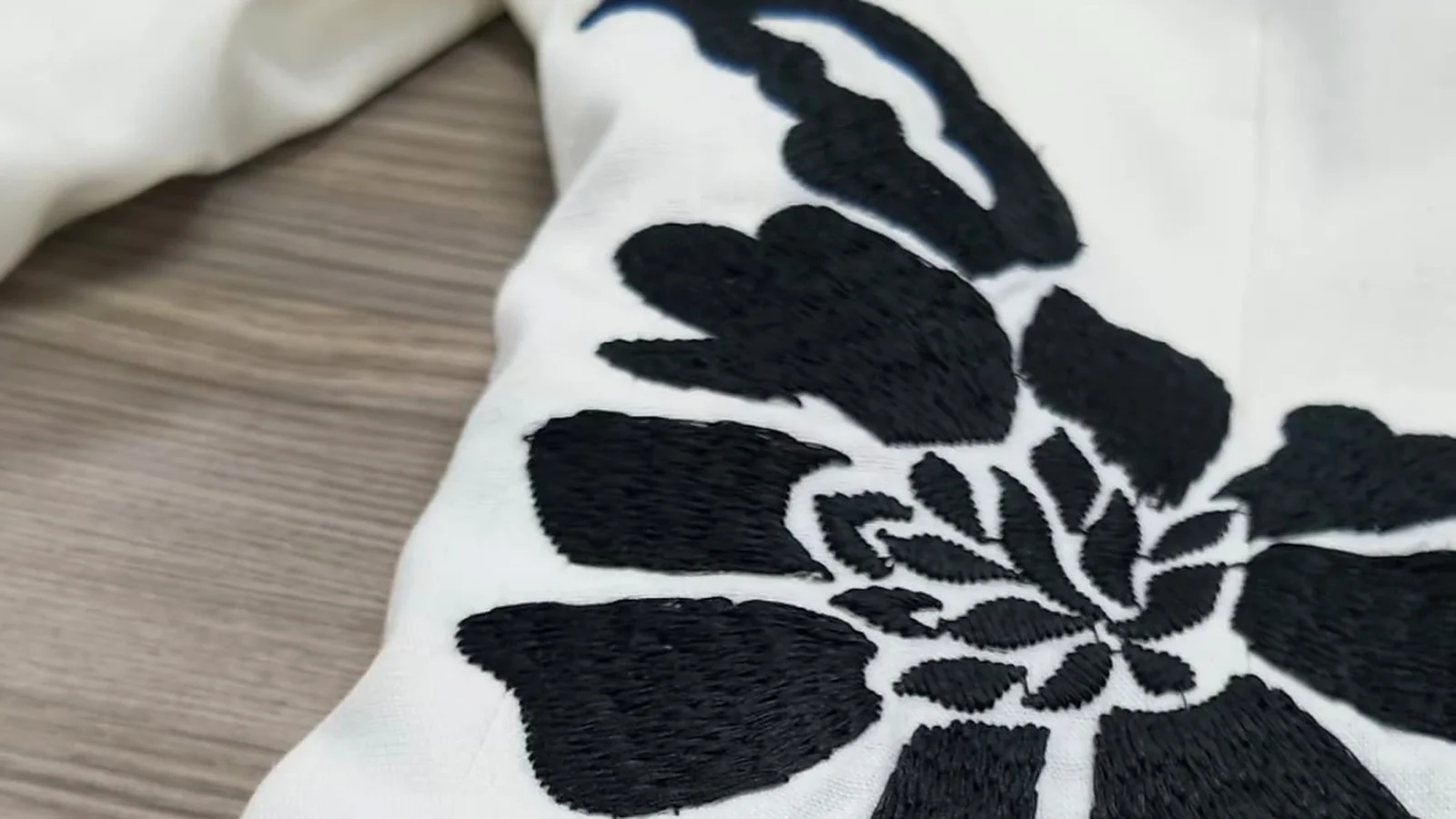 Black floral embroidery artwork on white fabric for scale review