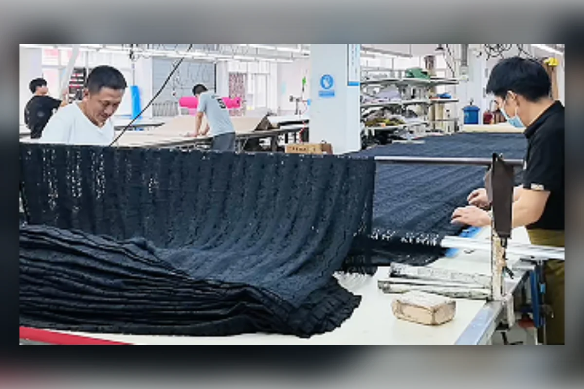 Workers handling multiple fabric layers for bulk garment cutting at Shengfu