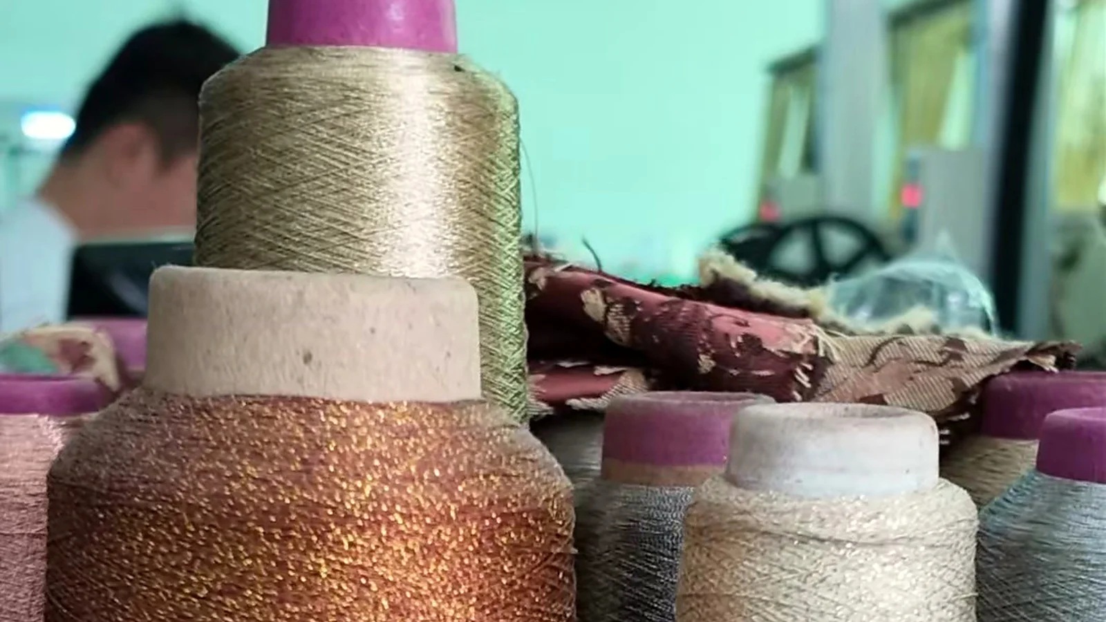 Metallic and neutral embroidery thread cones in a garment workshop