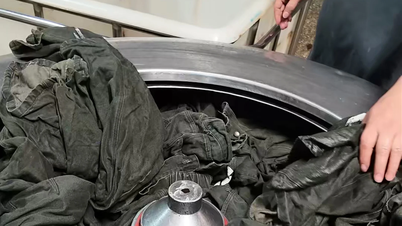 Black denim garments inside an industrial washing machine