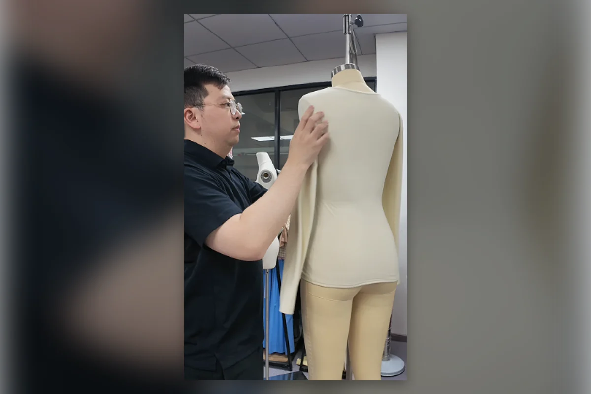 Shengfu technician checking fit and construction changes on a mannequin sample