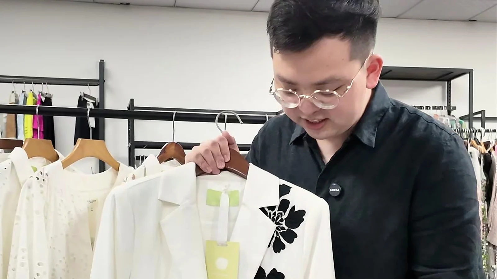 Shengfu specialist reviewing black floral embroidery on a white jacket