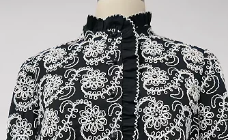 White floral embroidery on a dark garment collar and front