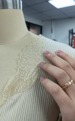 Hand positioning a lace motif on a dress form