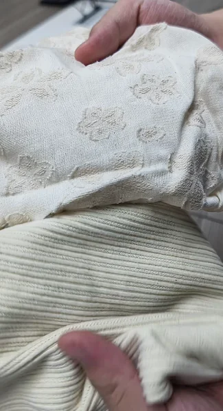 Hands comparing textured and ribbed fabric surfaces