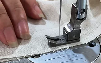 Close-up of fabric being stitched at a sewing machine