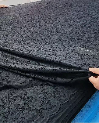 Dark patterned fabric held open for surface review
