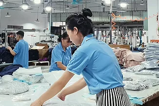 Worker handling garment pieces at a factory table