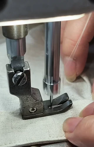 Sewing-machine foot stitching a light fabric edge
