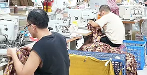 Workers handling patterned garments at a table