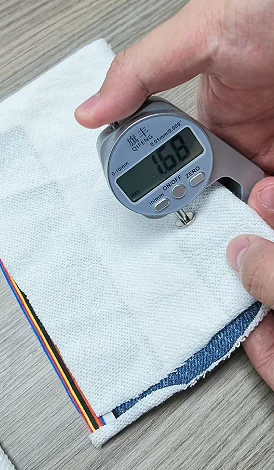 Digital thickness gauge measuring white fabric