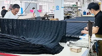 Two people holding a large piece of dark fabric
