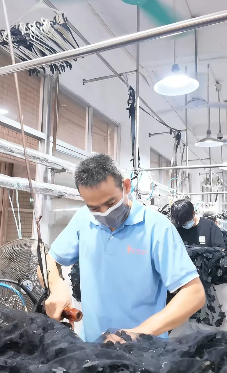 Worker handling a dark garment at a finishing station