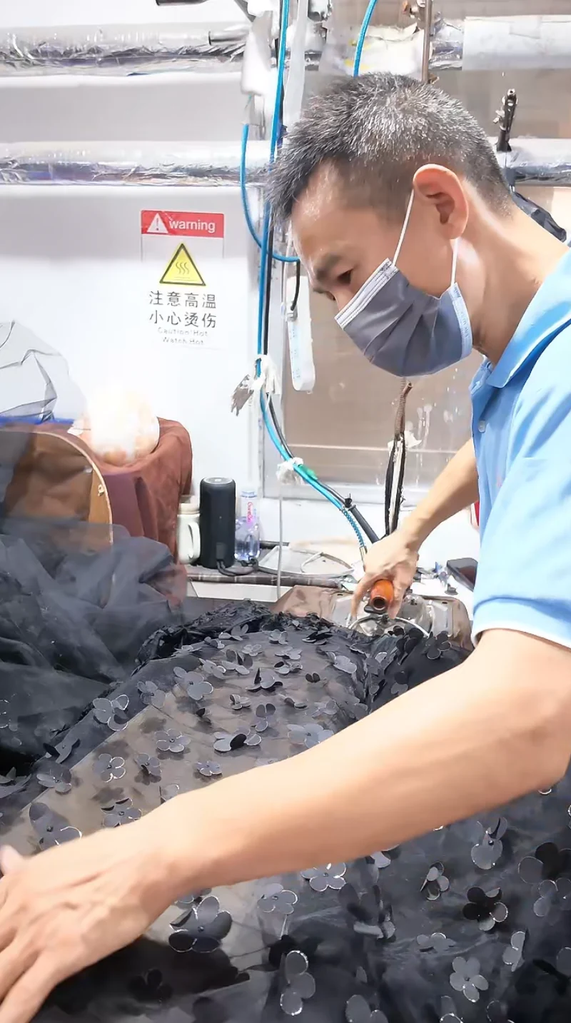 Worker handling dark garments at a finishing table