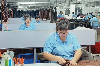 Worker sewing a light-coloured garment on a production line
