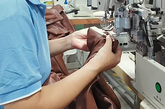 Close-up of hands guiding material at a sewing machine