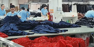 Workers handling dark garments beside a sewing machine
