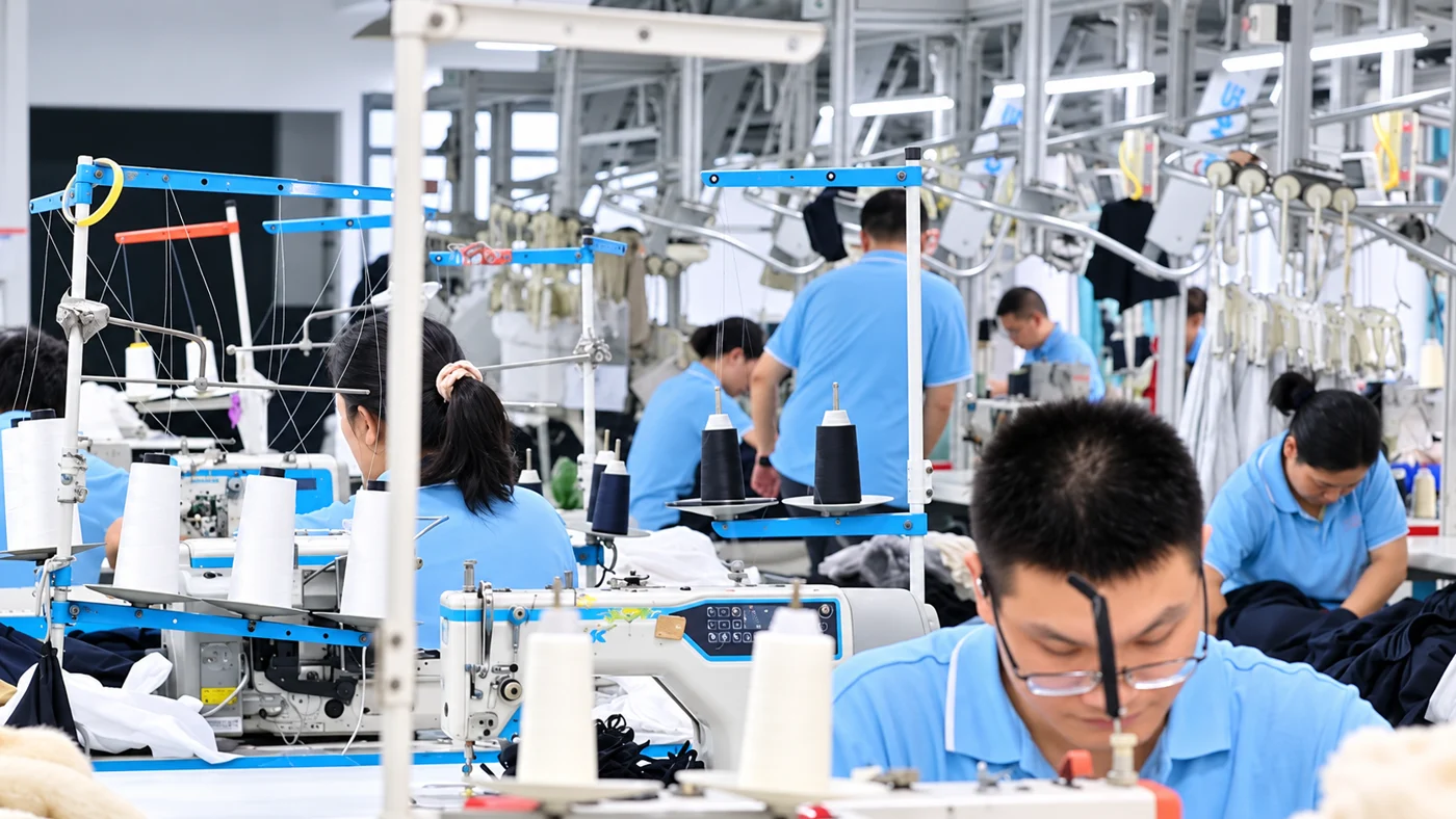 Workers at sewing stations on a garment production floor