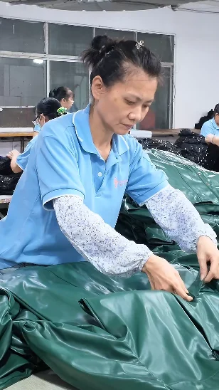 Worker handling green garments on a production table