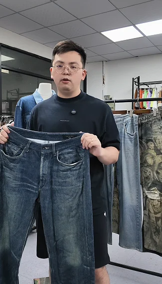 Man holding a denim-style garment for discussion