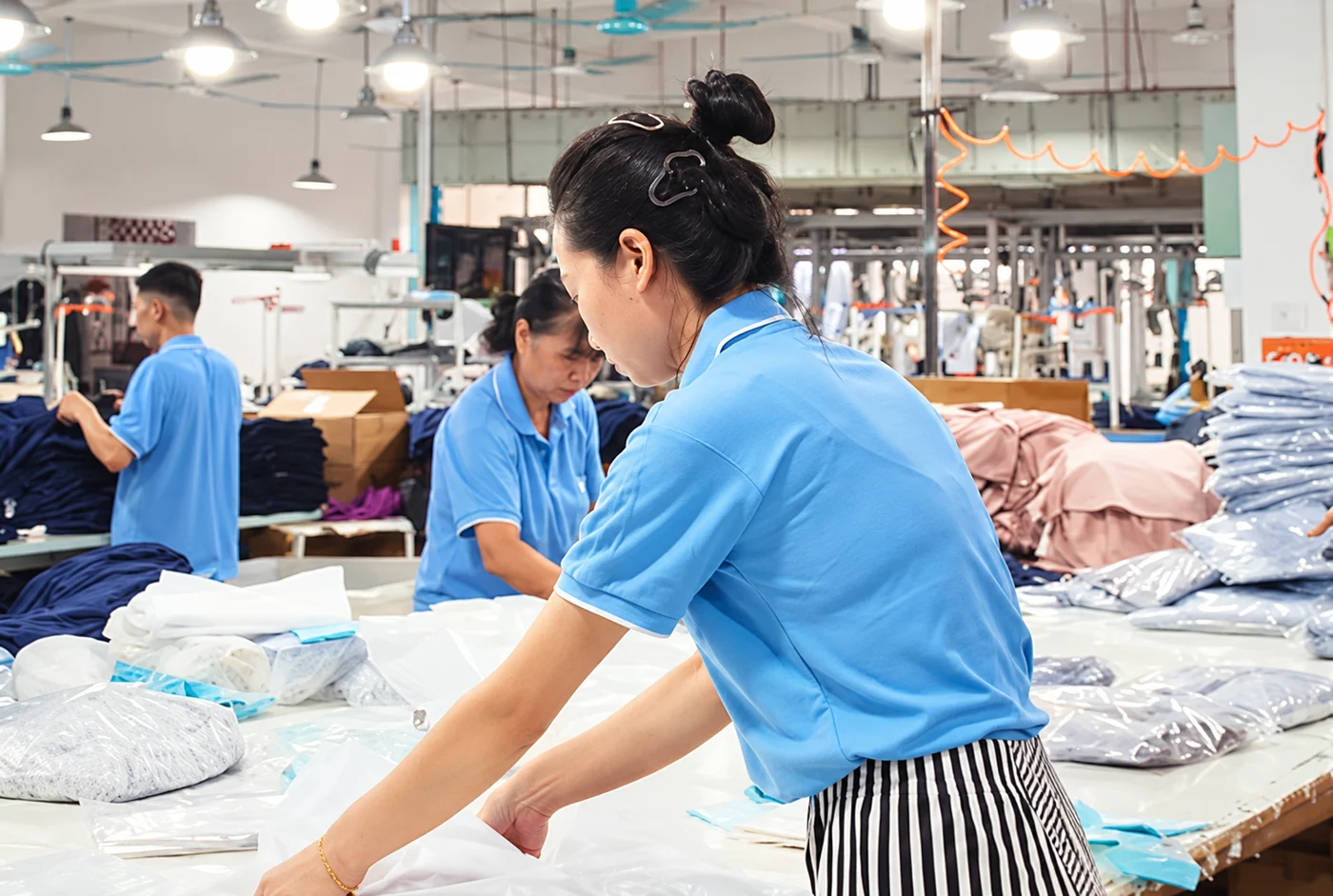 Worker arranging light garments at a production table