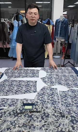 Man standing behind printed garment panels on a table