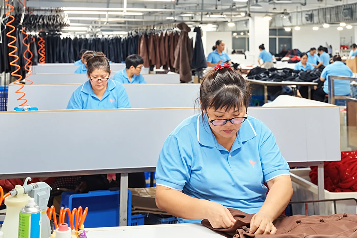 Worker sewing a brown garment on a production line