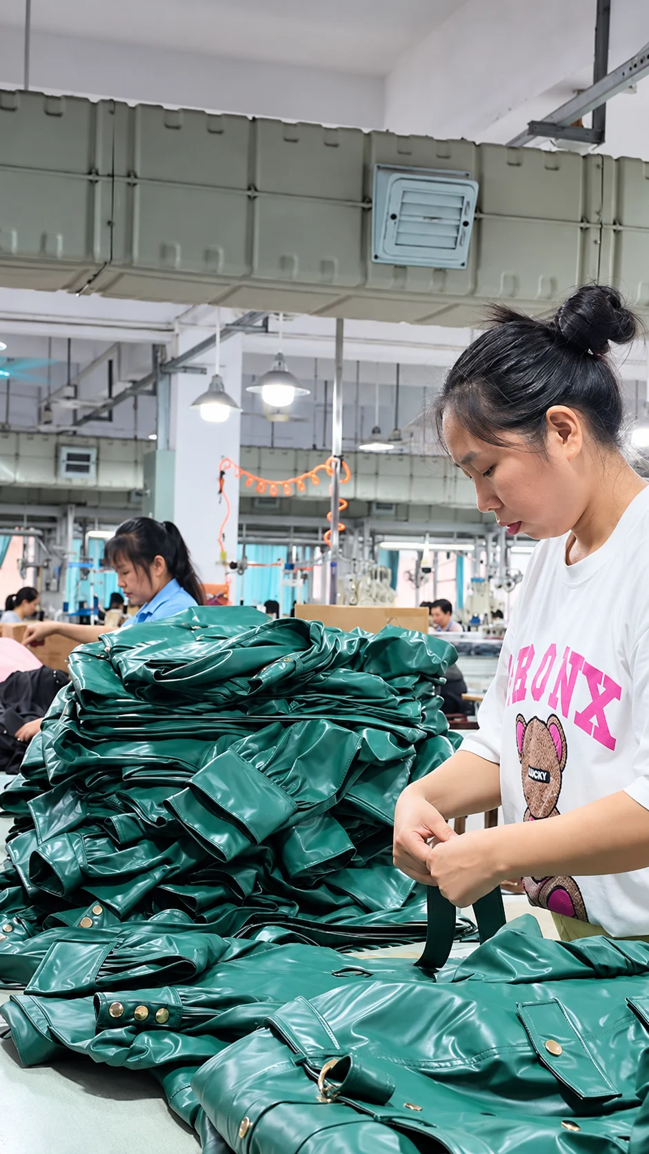 Worker handling green garments at a production table