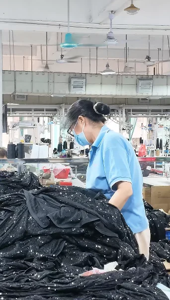 Worker arranging dark garments at a factory worktable