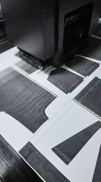 Printed garment panels moving beneath production equipment