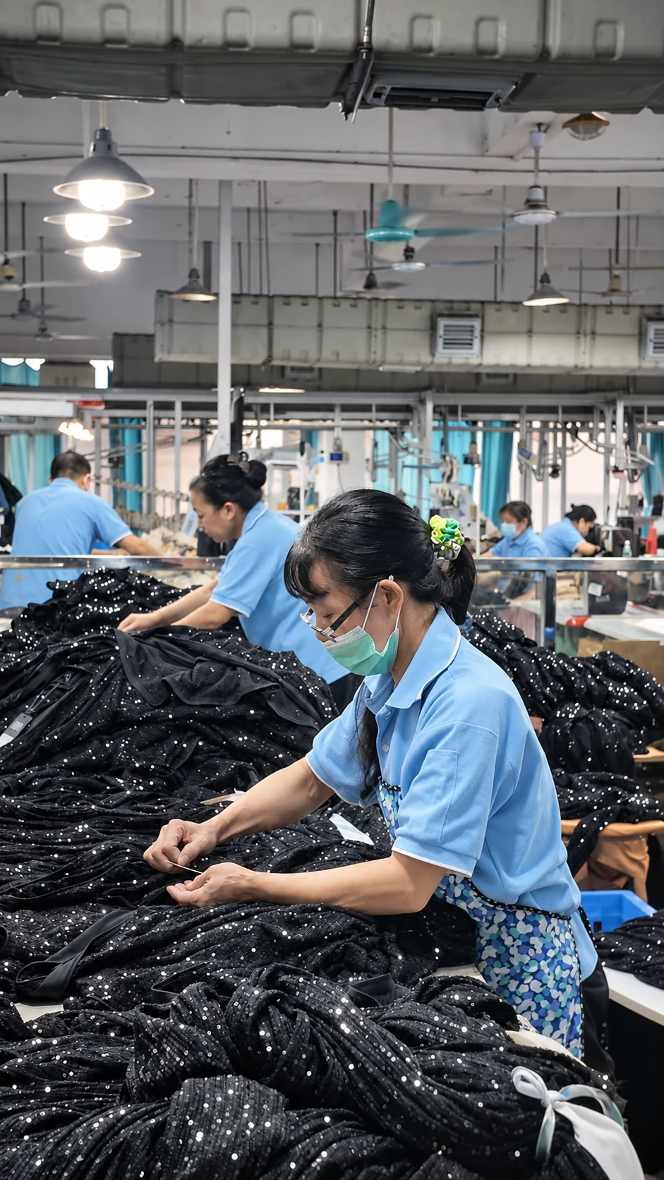 Worker handling dark garments at a production table