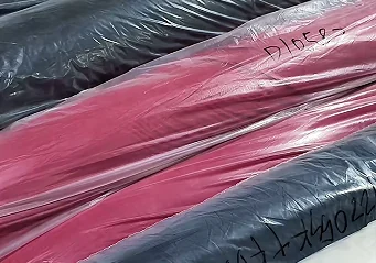 Wrapped coloured fabric rolls with handwritten identifiers