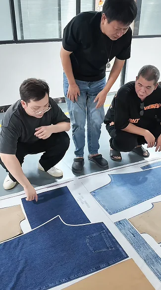 Team reviewing paper pattern pieces laid out on fabricI