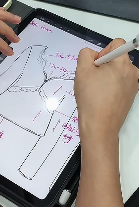 Hand adding measurements to a garment drawing on a tablet