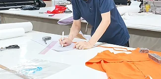 Pattern-development table with paper and an orange garment